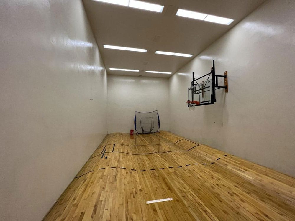 Indoor basketball court with wooden floor and hoop.