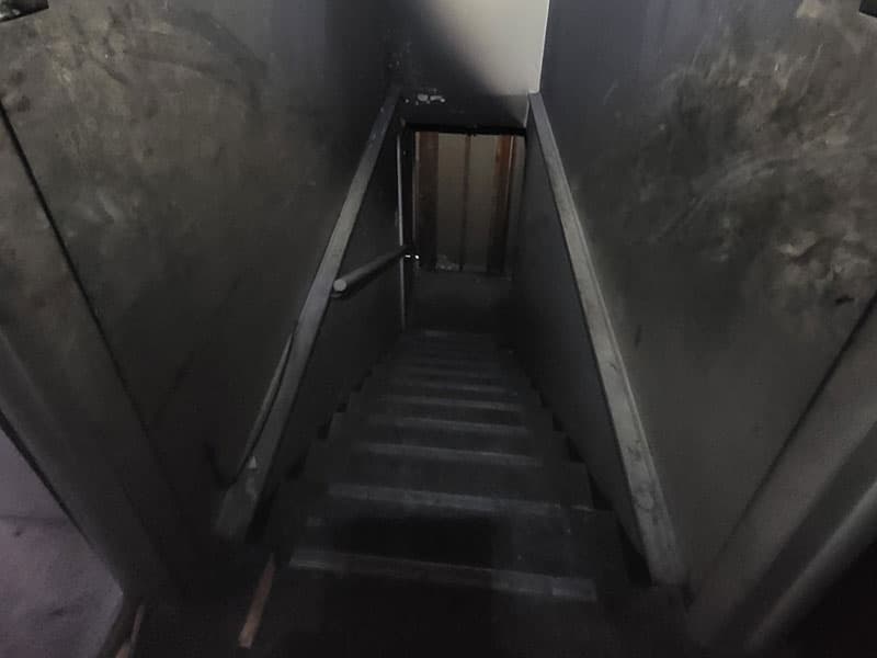 Dimly lit concrete stairwell with handrail.